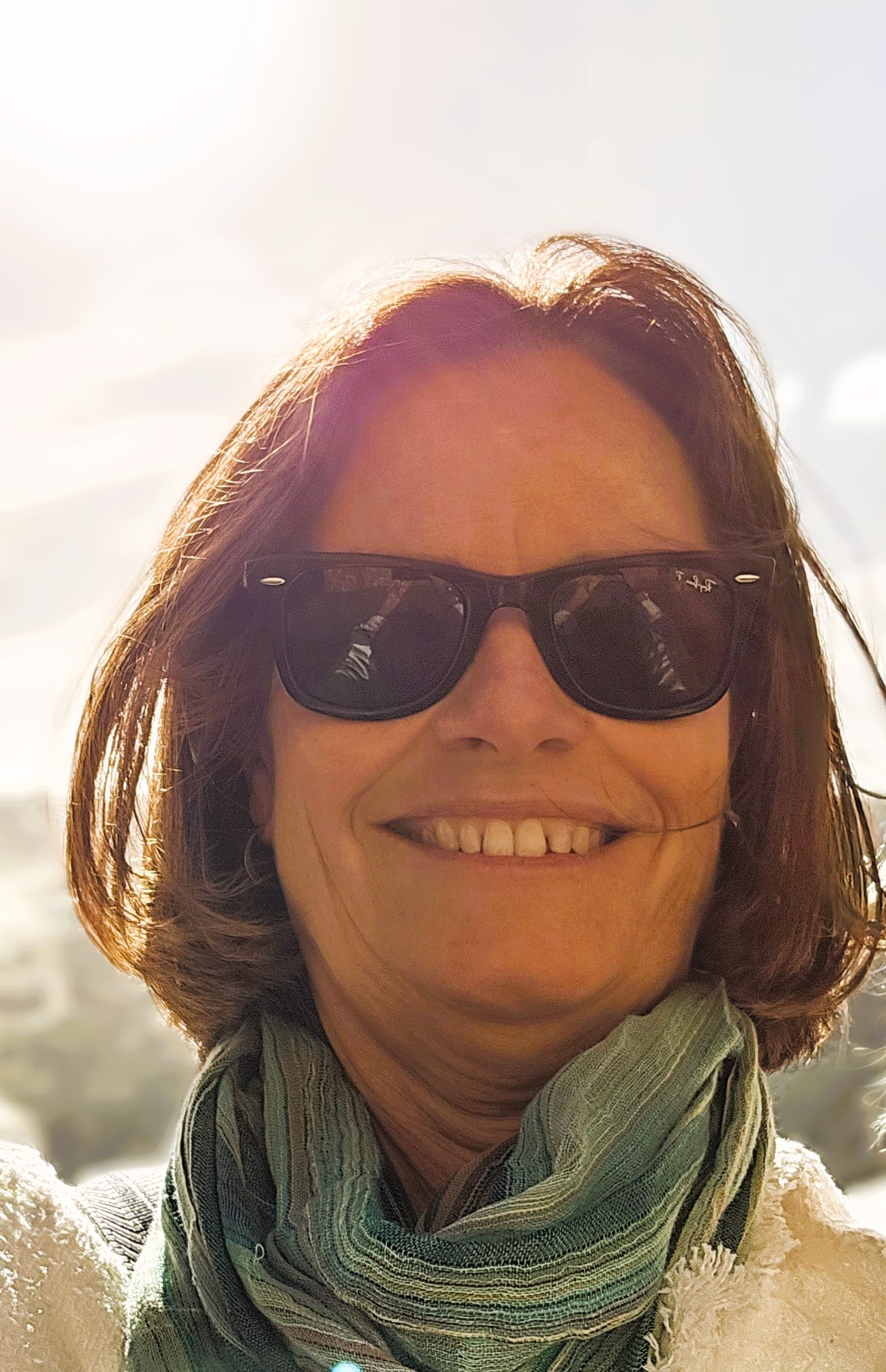 Katrina from Hi Tidy, smiling wearing sunglasses and a green scarf